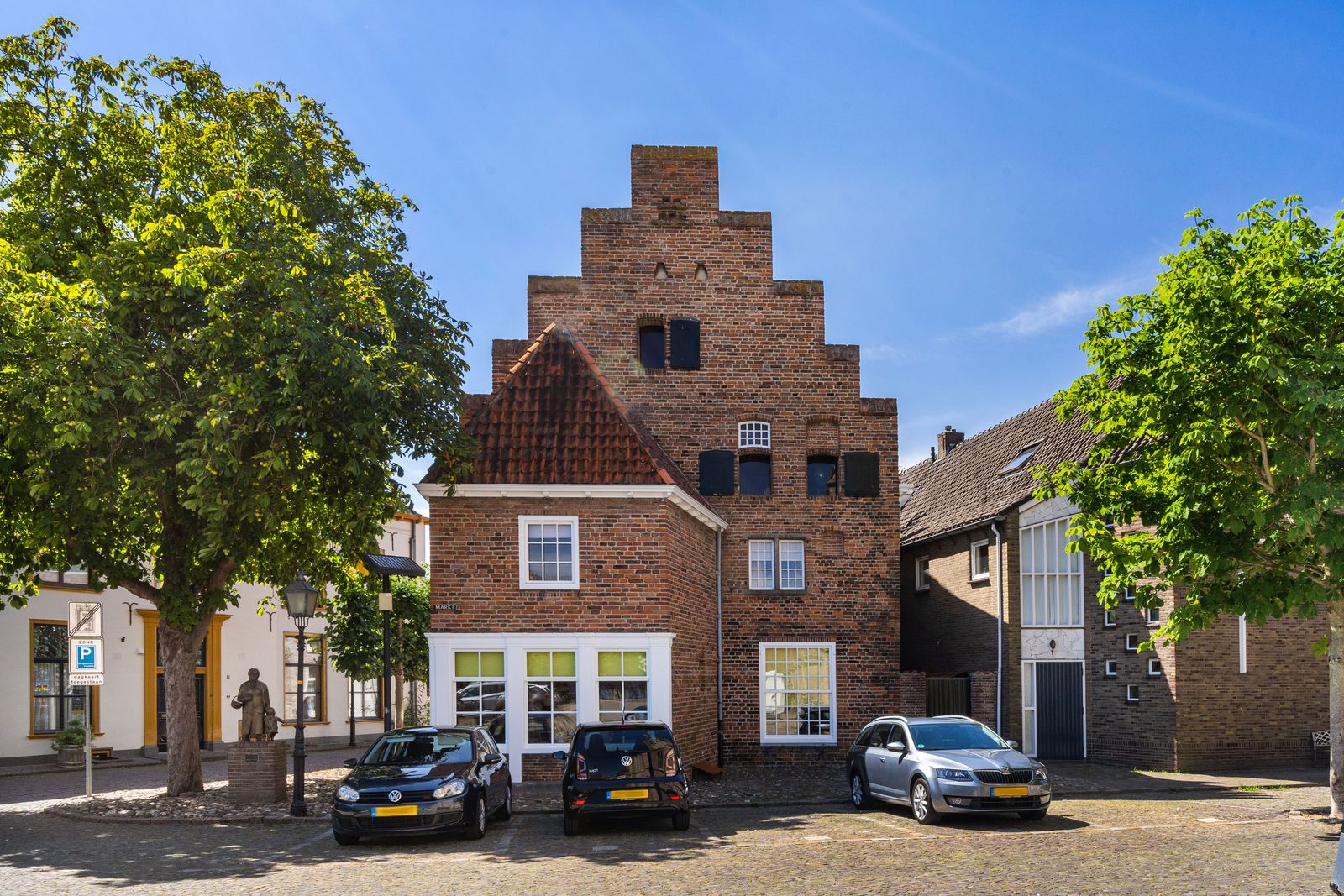 trapgevel van bakstenen aan een plein met bomen in Doesburg