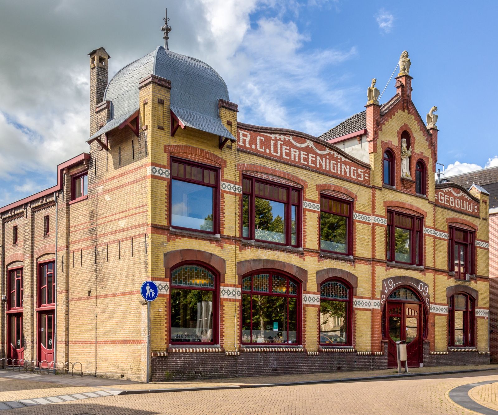 voormalige R.K. Verenigingsgebouw in Franeker, een gebouw van gele en rode baksteen met grote ramen, topgevels en een klein torentje met een grijs koepeldak