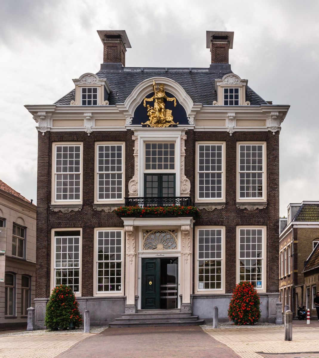 voorgevel van het raadhuis van Harlingen: bakstenen gevel met witte middenpartij, een balkon en een verguld stadswapen