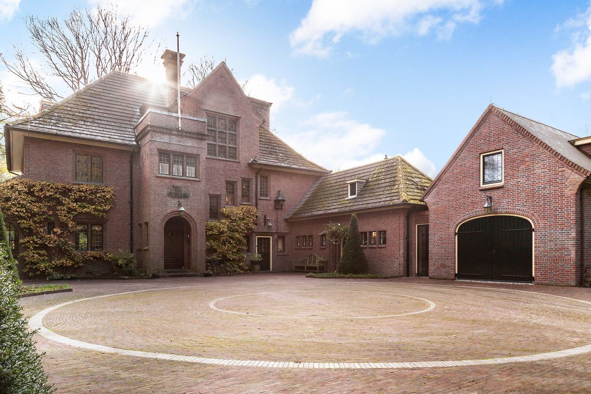 bakstenen landhuis met een bijgebouw rond een plein met klinkers in Heerde