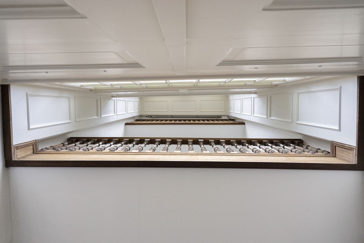 witte zaal met een galerij met balusters, van onderaf gezien