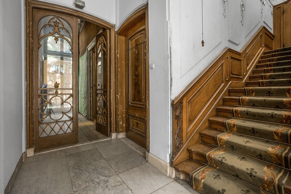 vestibule met een deur met gebrandschilderd glas, houten lambrisering en een trap met loper
