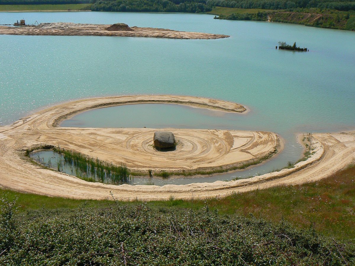land art van Robert Smithson in Emmen: een cirkel van zand in het water naast een heuvel
